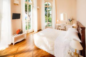 - une chambre avec un grand lit blanc et un bureau dans l'établissement Villa Sylva & Spa, à Sanremo