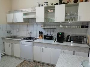 Eine Küche mit weißen Schränken, Spüle und Mikrowelle in der Unterkunft Casa Julia/Adult Only in Sovata