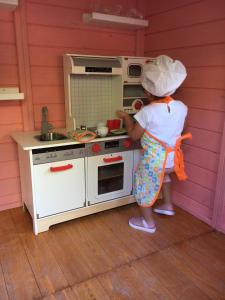 a little girl standing in front of a stove in a kitchen at Casa Moinho da Mouta in Parada de Pinhão
