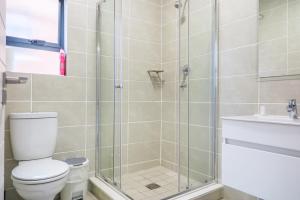 a bathroom with a shower with a toilet and a sink at Insaka's The Reid Apartment - Sandton in Sandown +7 photos