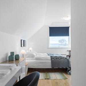 a white bedroom with a bed and a window at Strandsegård Ferielejlighed in Ølsted