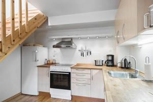 a kitchen with white appliances and a wooden floor at Strandsegård Ferielejlighed in Ølsted