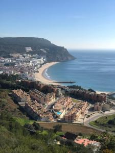 eine Luftansicht auf einen Strand mit Gebäuden und das Meer in der Unterkunft Casa amigavel da Terra in Sesimbra