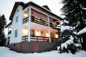 a house in the snow with lights on at Privilegio 148 Sâmbăta in Sâmbăta de Sus