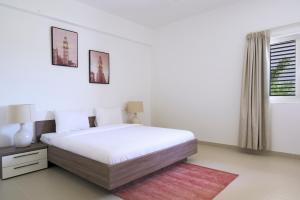 a white bedroom with a bed and a window at Le Sifah - Golf Lake Apartments in As Sīfah
