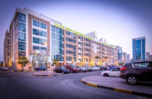 duży budynek z samochodami zaparkowanymi na parkingu w obiekcie Elite Seef Residence And Hotel w mieście Manama