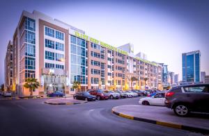 a large building with cars parked in a parking lot at Elite Seef Residence And Hotel in Manama