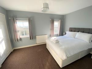 a bedroom with a white bed and two windows at Johnson Townhouse in Wellingborough
