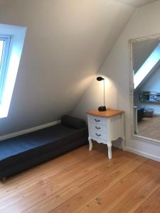 Cette chambre mansardée comprend un lit et un miroir. dans l'établissement Strandsegård Ferielejlighed, à Ølsted