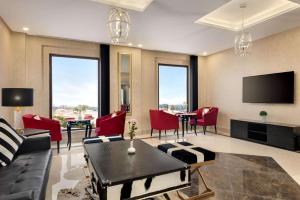 a living room with red chairs and a flat screen tv at Ramada by Wyndham Lahore Gulberg II in Lahore