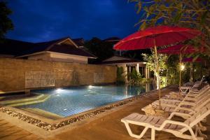 a swimming pool with chairs and a red umbrella at Clean Beach Resort in Ko Lanta