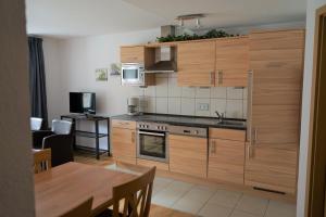 uma cozinha com armários de madeira, uma mesa e uma sala de jantar em Haus Moselliebe B&B em Ediger-Eller