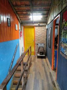 a hallway with a yellow door and stairs in a building at Chalés Caminhos Do Rosa in Praia do Rosa