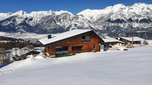 a log cabin in the snow with mountains in the background at Gschwendtalm Tirol - Luxus-Apartment für Ihre Auszeit in Tulfes