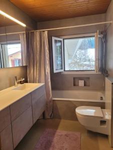 a bathroom with a toilet and a sink and a window at Villa Castagna Guesthouse in Luzern