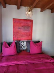 a bedroom with pink pillows and a painting on the wall at Villa Castagna Guesthouse in Lucerne