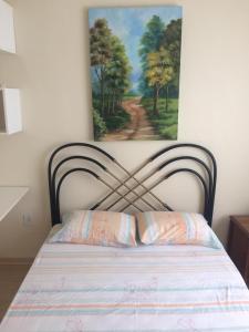 a bedroom with a bed with a painting on the wall at Pedra do Imperador - Apartamento in Nova Friburgo