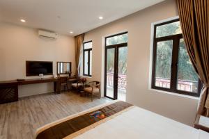 a bedroom with a bed and a desk and windows at Korea Hotel Bac Giang in Làng Thành