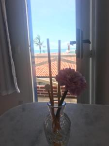 un vaso con fiori viola seduto su un tavolo di Pousada America do Sol a Natal