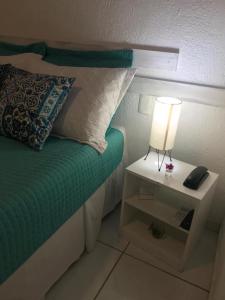d'un lit avec une table de nuit et une lampe. dans l'établissement Pousada America do Sol, à Natal