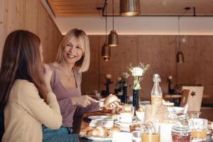 ダーミュルスにあるHotel Alpensternの二人の女がテーブルに座って食べ物を食べている