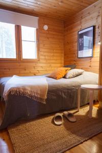 a bed in a wooden room with a table and shoes at Katve Nature Retreat in Kirkkonummi