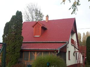 a red roof on a house with a tree at Tiszai Vándor Apartmanház in Kisköre