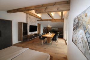 a living room with a table and chairs and a television at Apartmenthaus Vergissmeinnicht in Abtenau