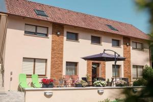 a house with a patio with an umbrella and chairs at Erika Vendégház in Mogyoród