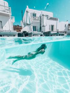 - un dauphin nageant dans une piscine en face d'une maison dans l'établissement Mykonos Princess Hotel, à Agios Stefanos