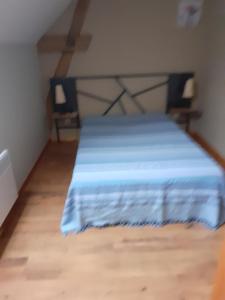 Un dormitorio con una cama con una manta azul. en Meublé de campagne au calme, en Louchy-Montfand