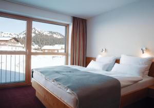 a bedroom with a large bed and a large window at Hotel Alpenstern in Damuls
