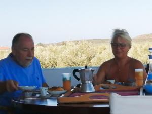 Ein Mann und eine Frau sitzen an einem Tisch mit Essen in der Unterkunft Megris Country Houses in Vingláfia