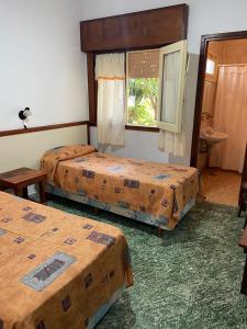 a hotel room with three beds and a window at Hotel Roma in Mar de Ajó +8 photos