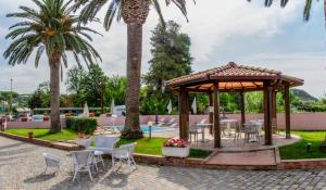 een prieel met tafels en stoelen en palmbomen bij Hotel Villa Rosa in Porto Azzurro