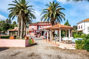 ein Haus mit Palmen und einem Pavillon in der Unterkunft Hotel Villa Rosa in Porto Azzurro