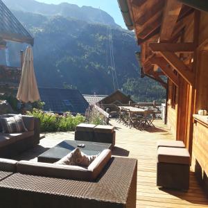 a patio with a couch and an umbrella and a table at Chalet Skidh - 10 personnes - emplacement idéal au centre de Vaujany in Vaujany