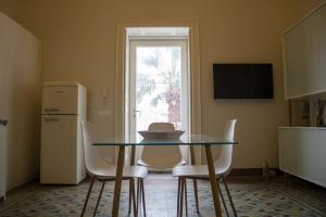 a kitchen with a glass table and chairs and a refrigerator at Salgari Uno in Marina di Ragusa