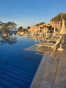 a swimming pool with tables and umbrellas in the water at Apartmaji Punta in Veli Lošinj
