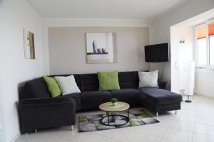 uma sala de estar com um sofá preto e uma mesa em FeWo Tietjen-Lohse, mit Meerblick, Strandhochhaus F9 em Cuxhaven