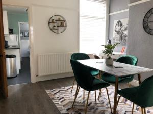 a dining room with a table and green chairs at Coventry Cosy House, City Centre, Free Parking, Sleeps 5, by EMPOWER HOMES in Coventry