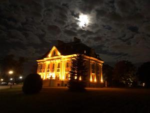 a house lit up at night with a full moon at Hotel Pałac Borynia in Jastrzębie Zdrój