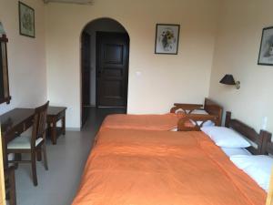 two beds in a room with a table and a door at Vontzos Hotel in Achladies