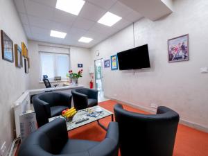 a waiting room with chairs and a table and a tv at Apartmany Style in Prešov