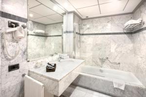 Baño blanco con bañera y lavamanos en Hotel Gran Via, en Logroño