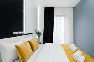 a bedroom with a white bed with yellow pillows at Bed&Bath Luxury Apartments in Krakow