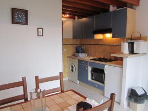uma cozinha com um fogão, uma mesa e cadeiras em Gite Les Oyats em Cancale
