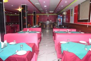 a restaurant with pink and blue tables and chairs at Hotel Om International in Bodh Gaya