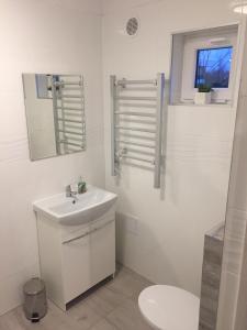 Baño blanco con lavabo y aseo en Westbeach House, en Grzybowo