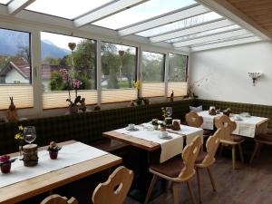 a dining room with tables and chairs and windows at Gästehaus Pöppl in Unterwössen